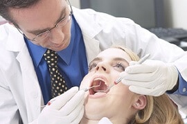 Dentista examinando boca de mulher