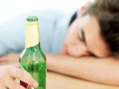 Homem dormindo segurando garrafa de cerveja