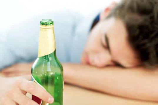 Homem dormindo segurando garrafa de cerveja