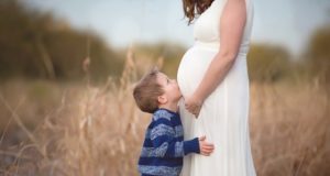 Menino bejando barriga de grávida de sua mãe