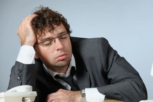 Homem de terno cohcilando no trabalho